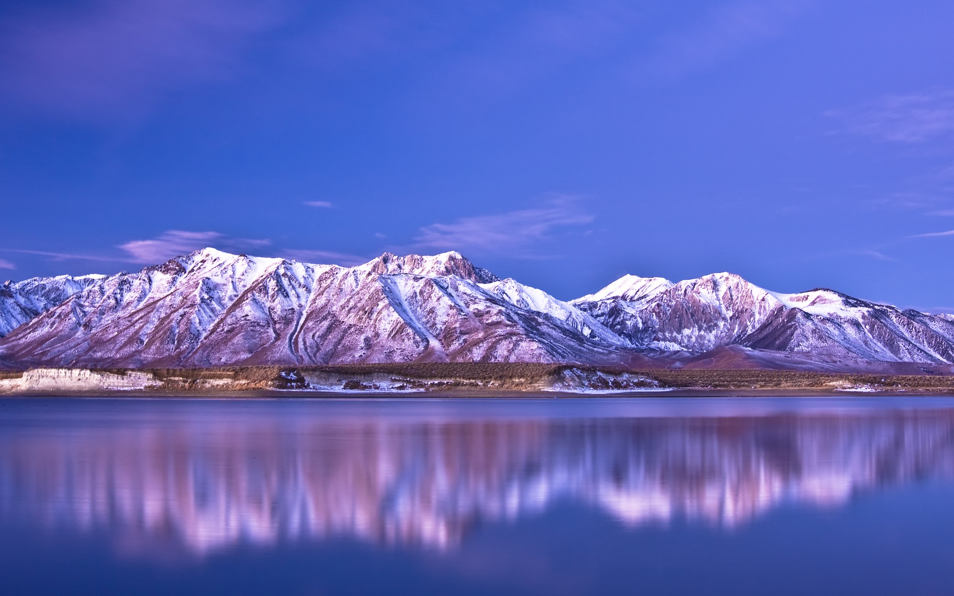 Snow-capped mountains reflected in a calm lake HD Wallpaper