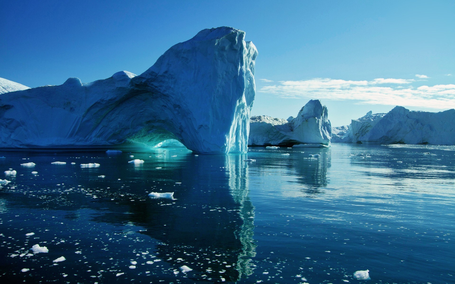 Icebergs floating in the ocean under a clear blue sky HD Wallpaper