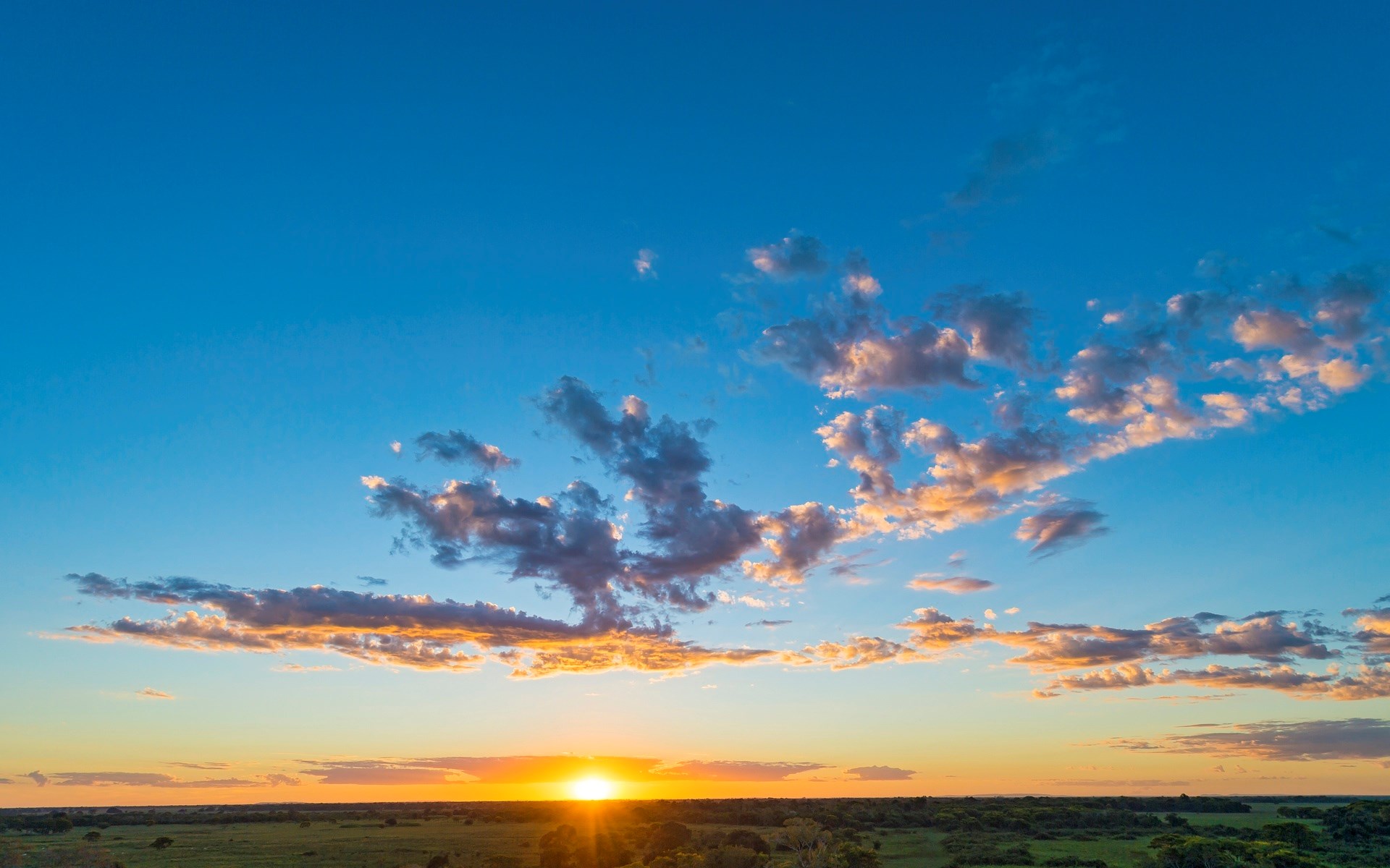 Sunset over a green landscape with clouds HD Wallpaper
