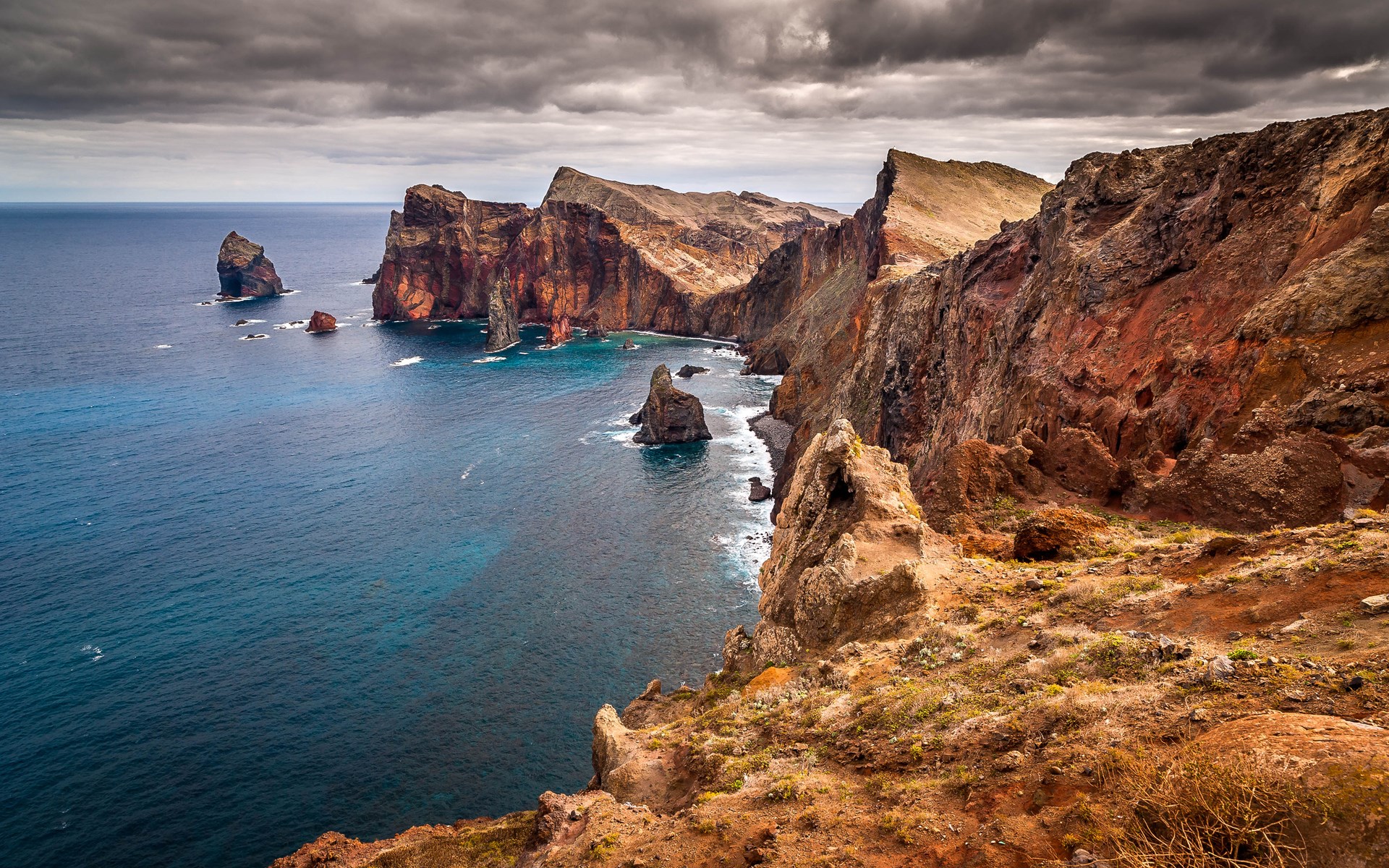 Rocky coastline with sea stacks under cloudy sky HD Wallpaper