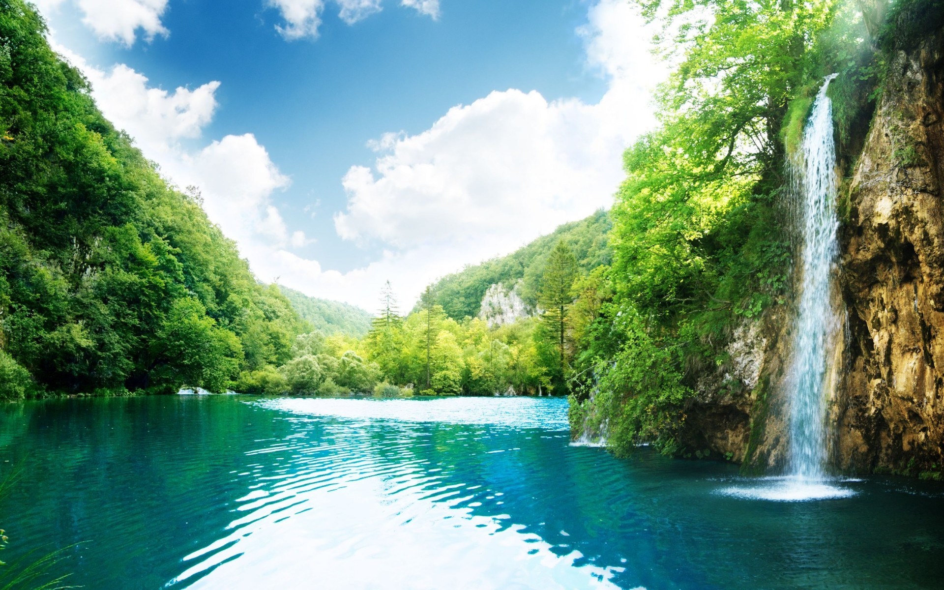 Waterfall cascading into a turquoise lake surrounded by green trees HD Wallpaper