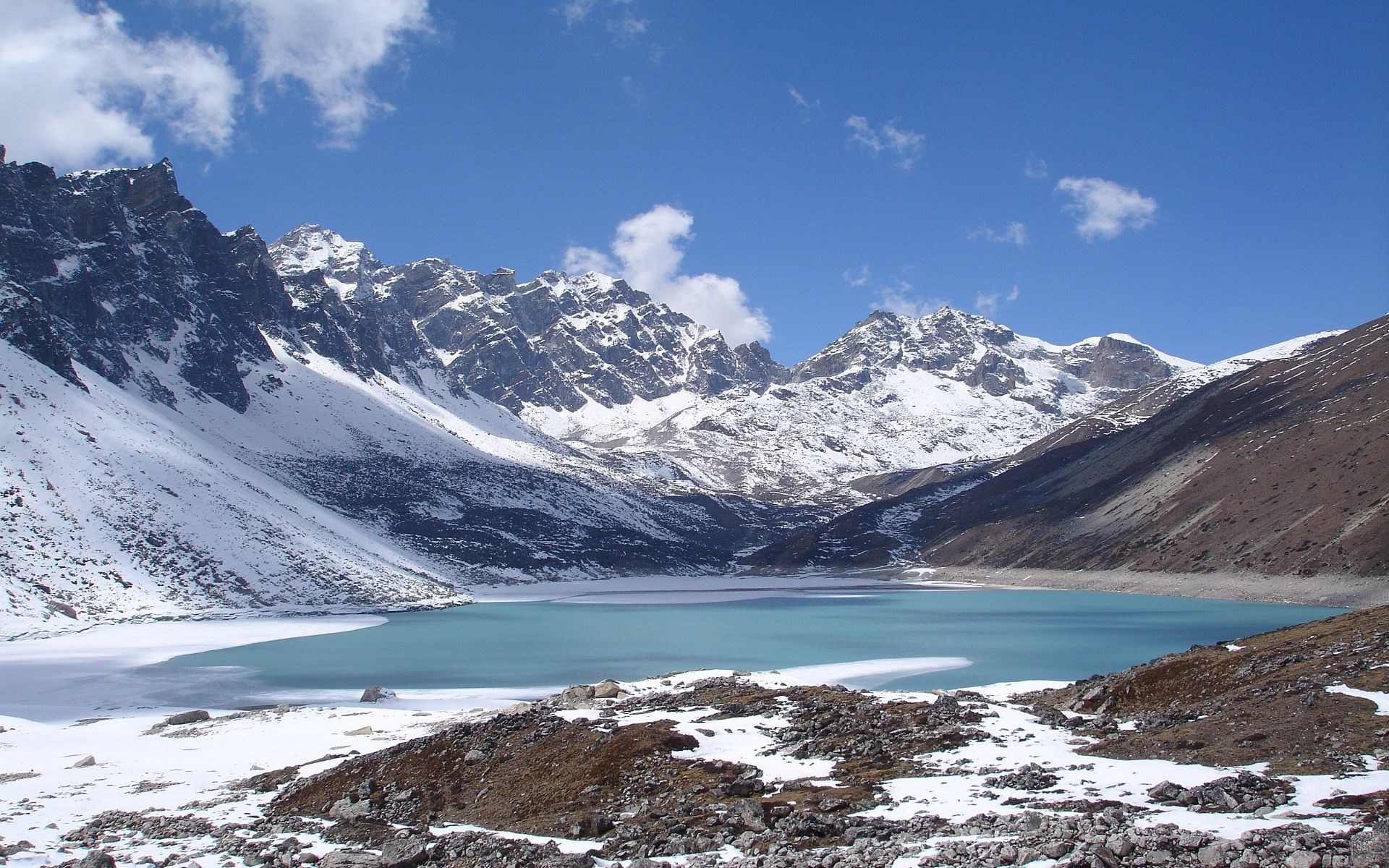 Turquoise lake surrounded by snow-capped mountains HD Wallpaper