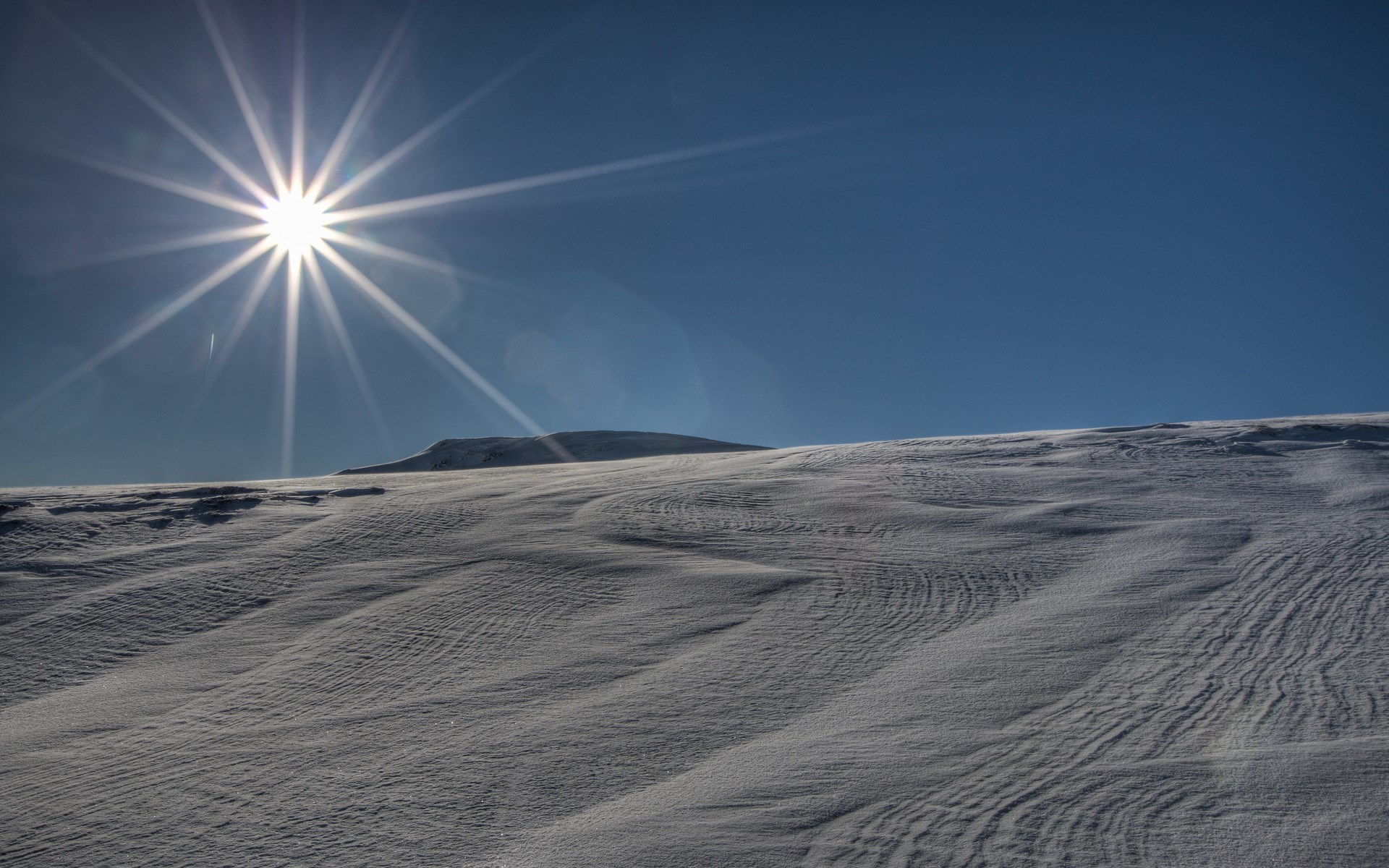 Sunburst over snow-covered hills HD Wallpaper