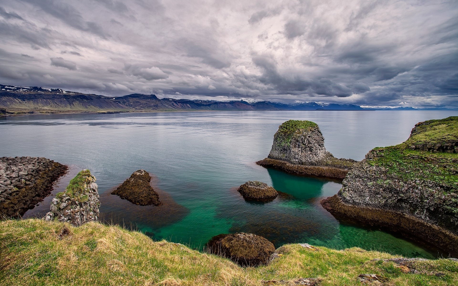 Rocky coastline with green grass and turquoise water HD Wallpaper