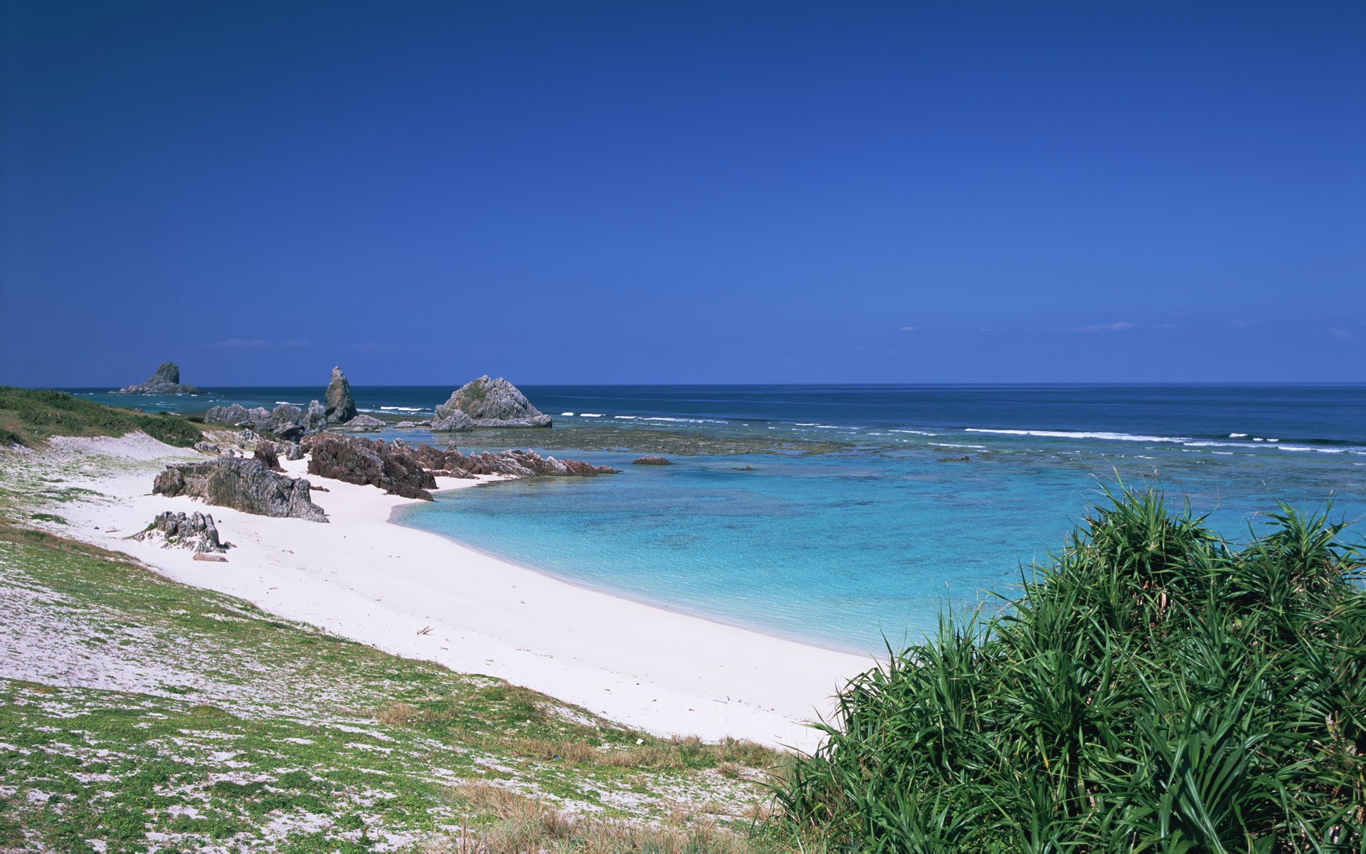 Tropical beach with rocky outcrops and clear blue water HD Wallpaper