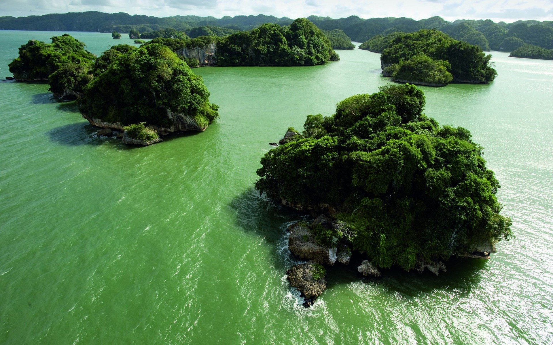 Islands covered in lush green trees in a turquoise bay HD Wallpaper