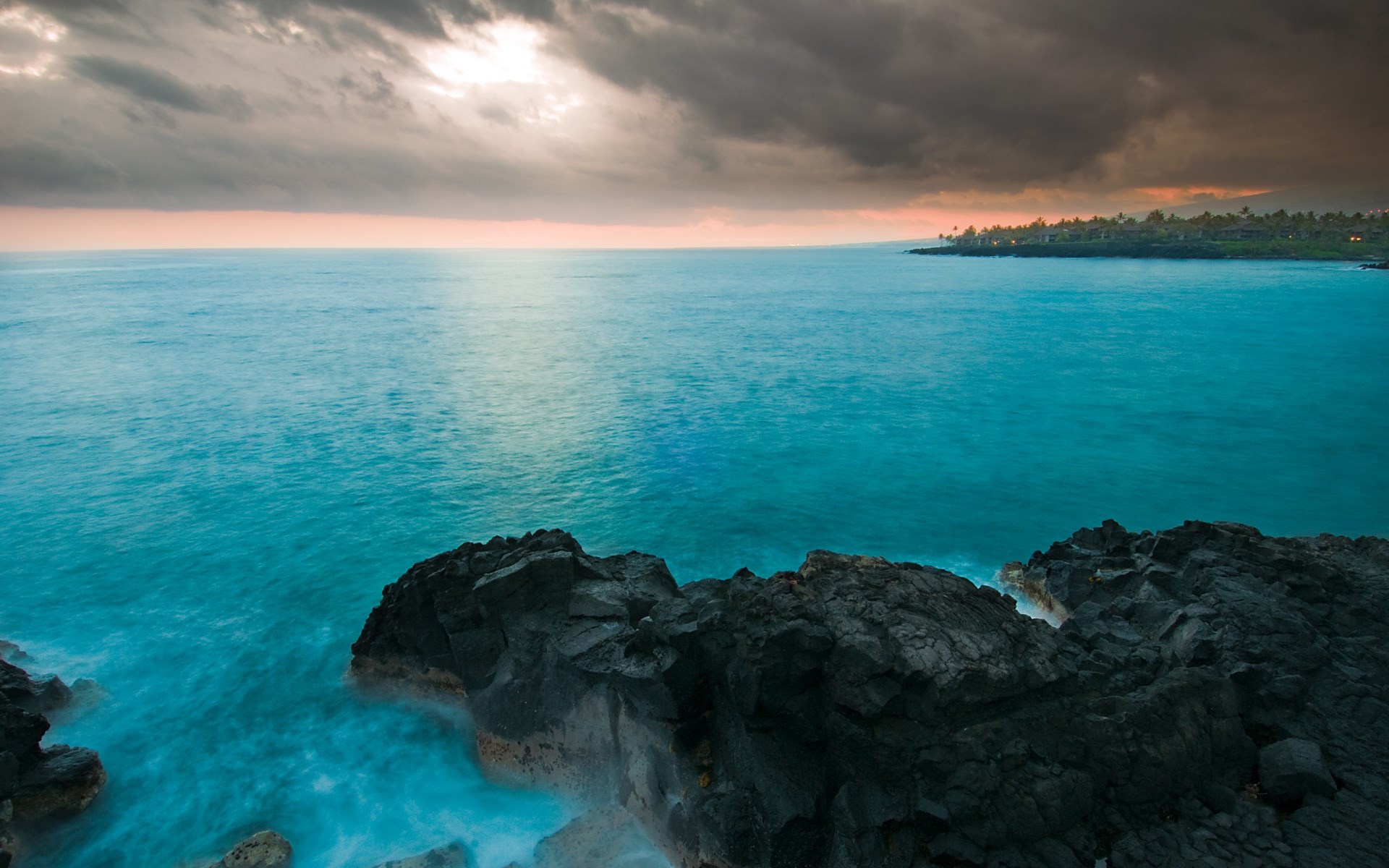 Ocean waves crash against dark rocks near a coastline HD Wallpaper