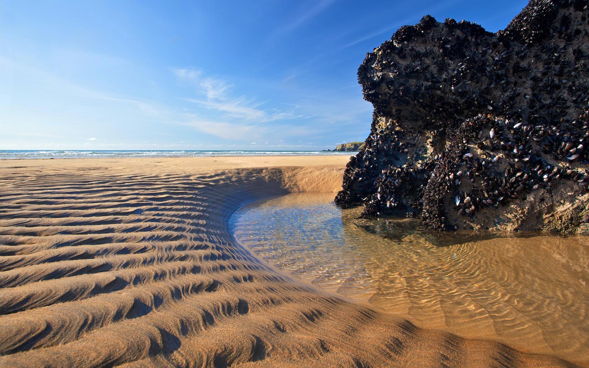 Tidal pool on a sandy beach with rock formation HD Wallpaper