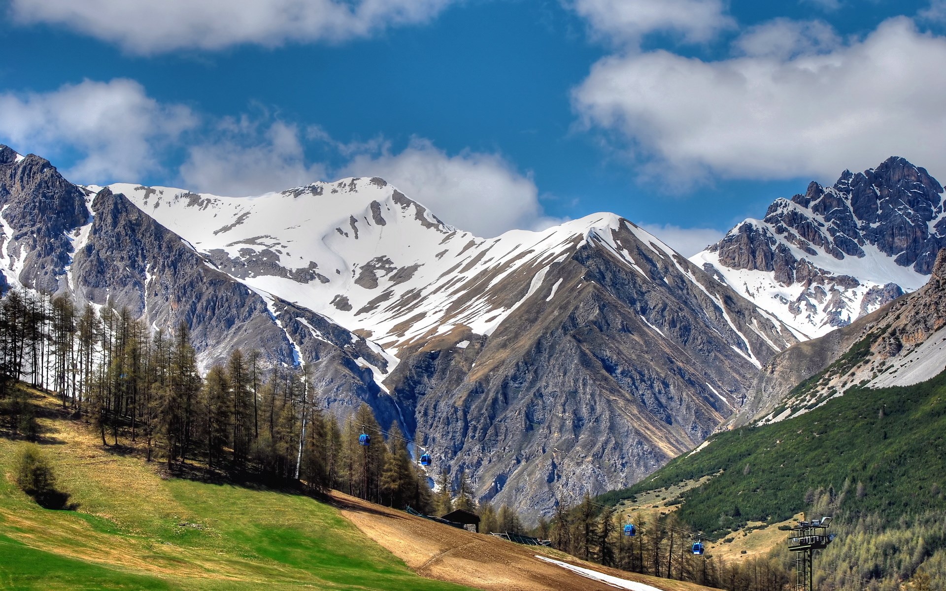 Cable cars ascend a snowy mountain valley HD Wallpaper