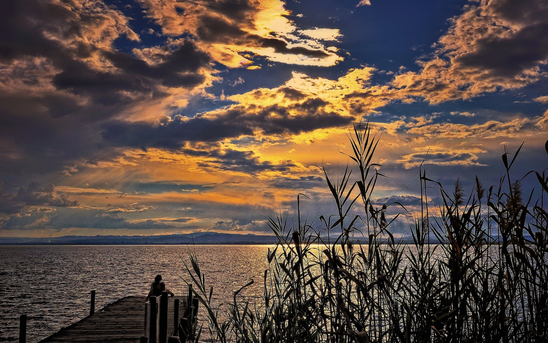Sunset over lake with person on pier and reeds HD Wallpaper