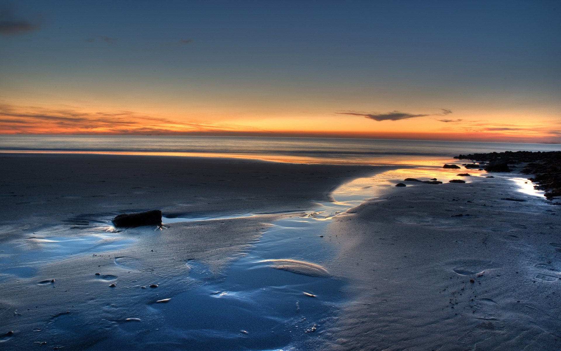 Beach at sunset with calm ocean and wet sand HD Wallpaper