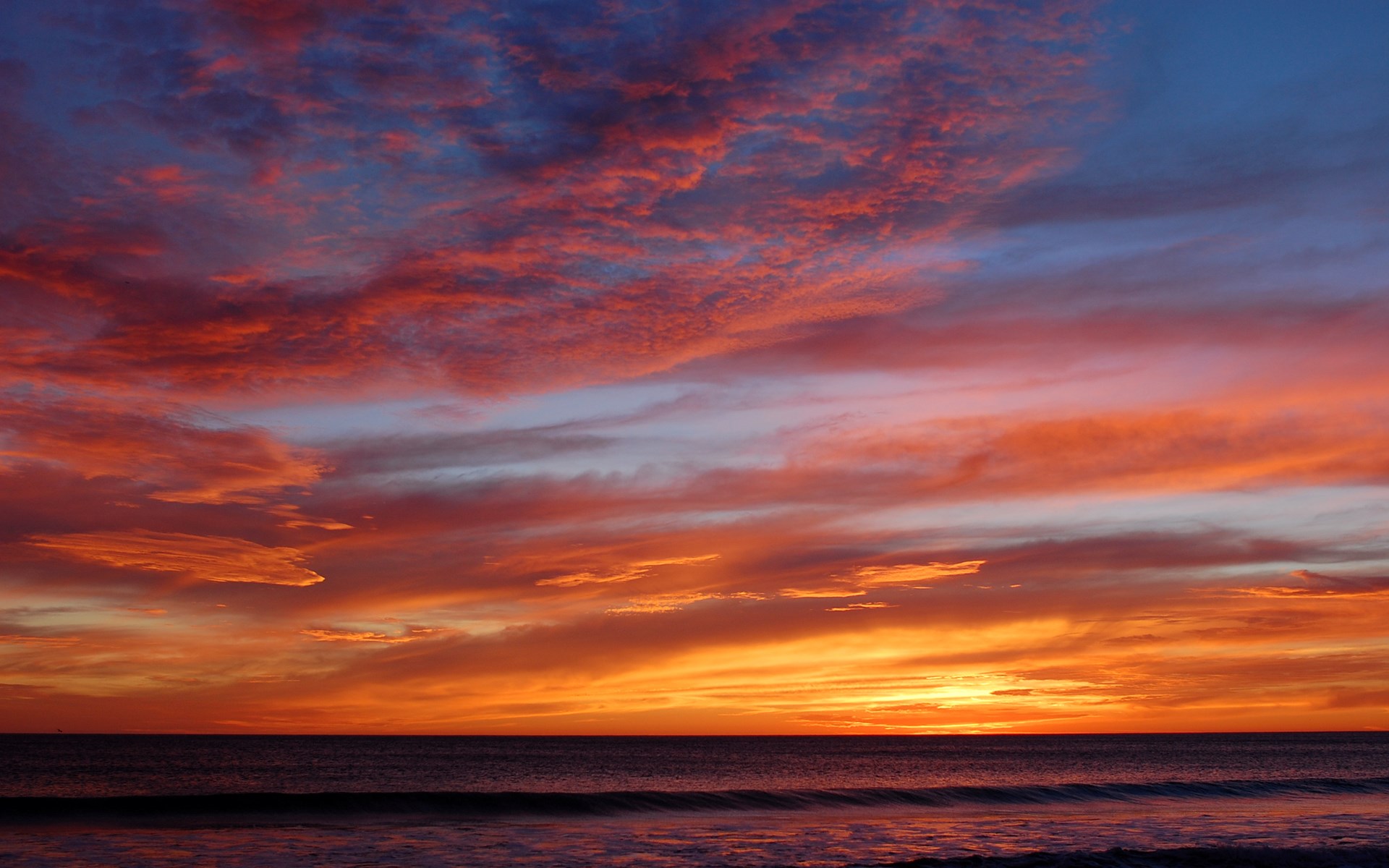 Fiery sunset over the ocean with dramatic clouds HD Wallpaper
