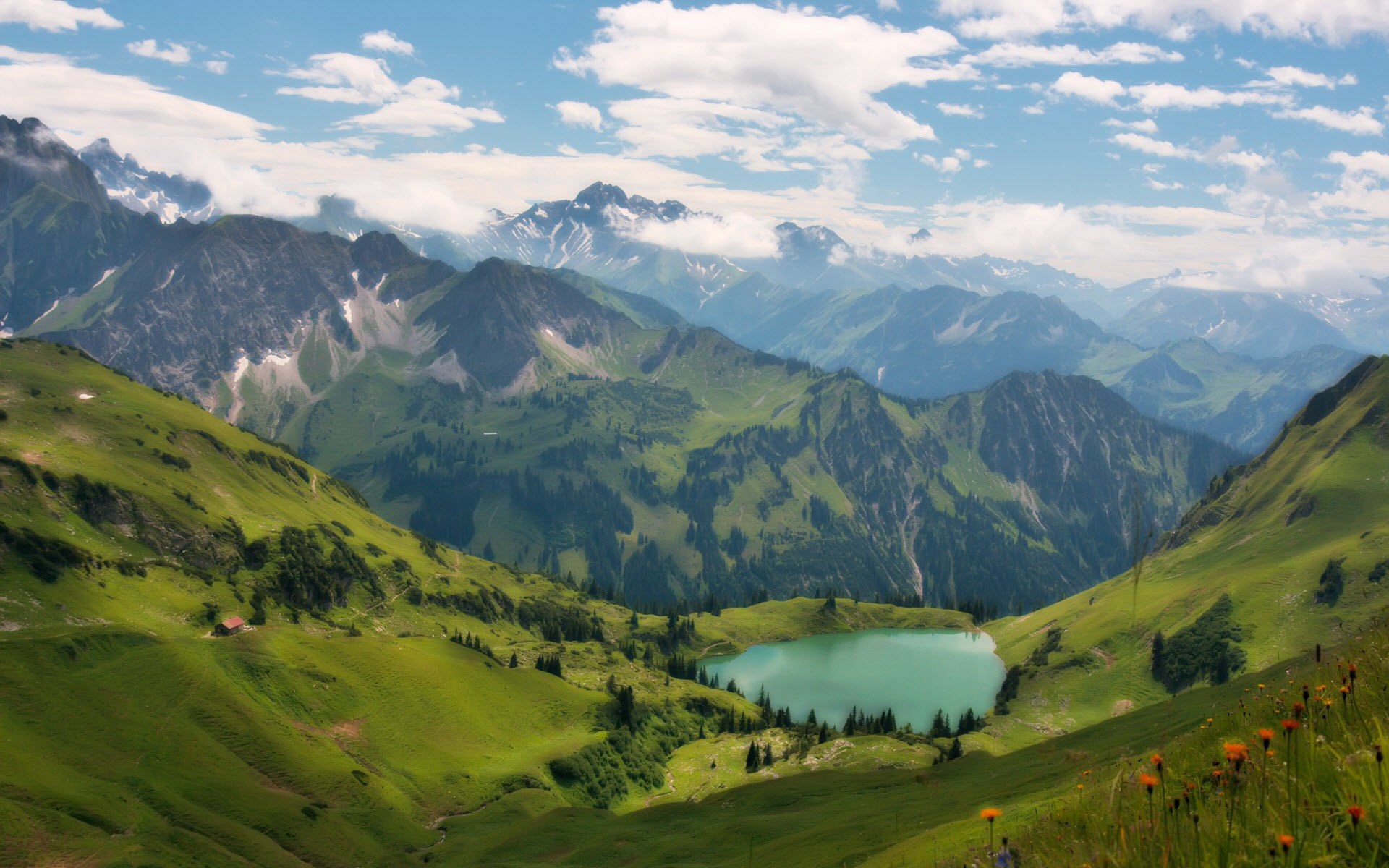 Alpine lake surrounded by green mountains and cloudy sky HD Wallpaper