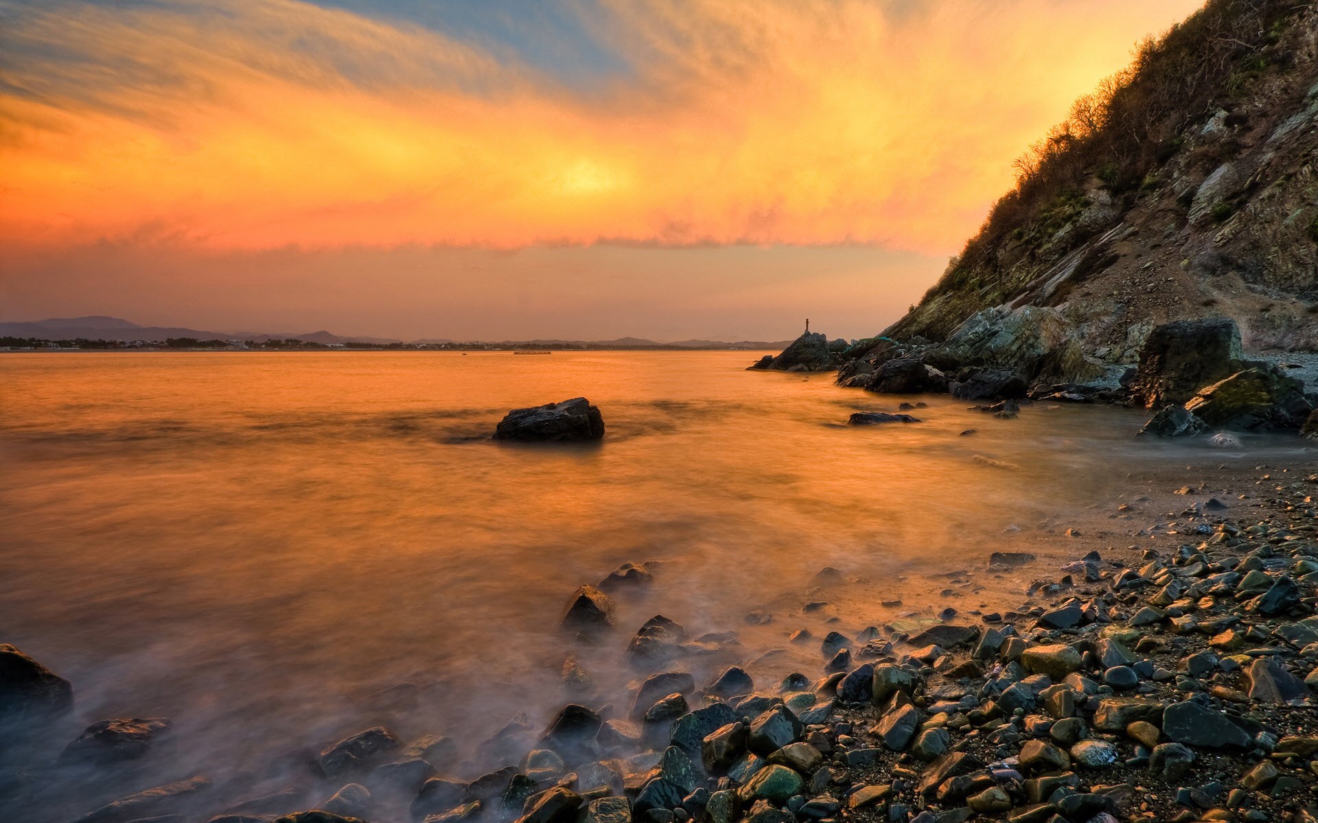 Sunset over a rocky coastline with calm water HD Wallpaper