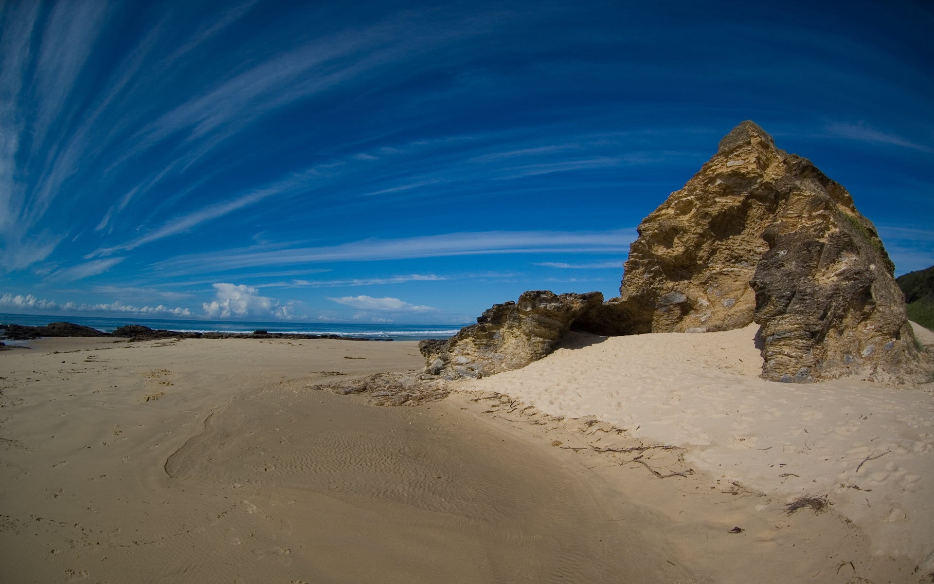 Sandy beach with rock formations and blue sky HD Wallpaper