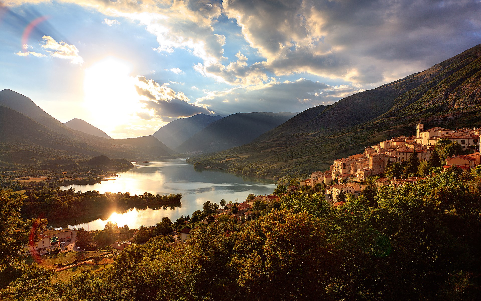 Village on a hill overlooking a lake at sunset HD Wallpaper