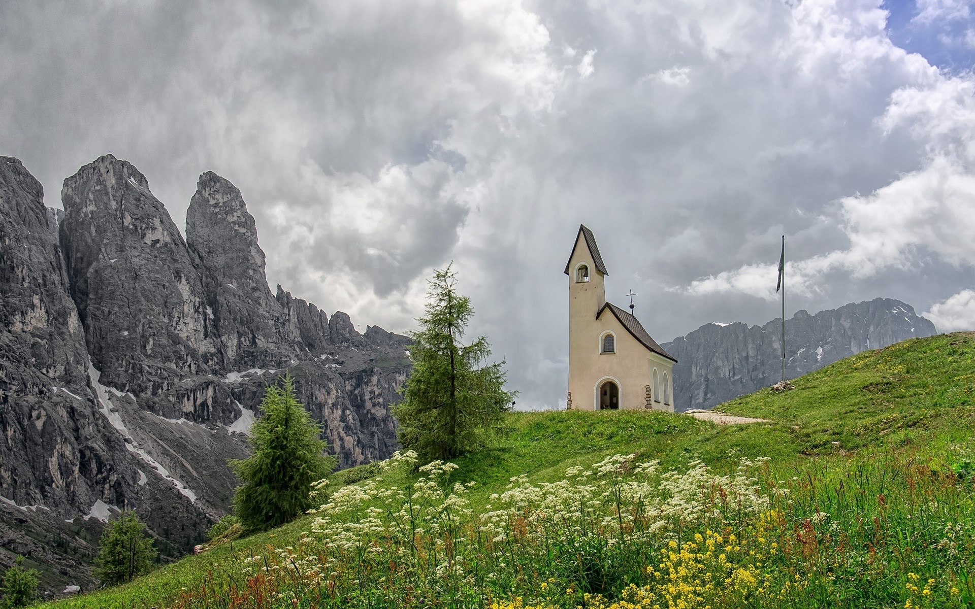 Chapel on a grassy hill with mountains and clouds HD Wallpaper
