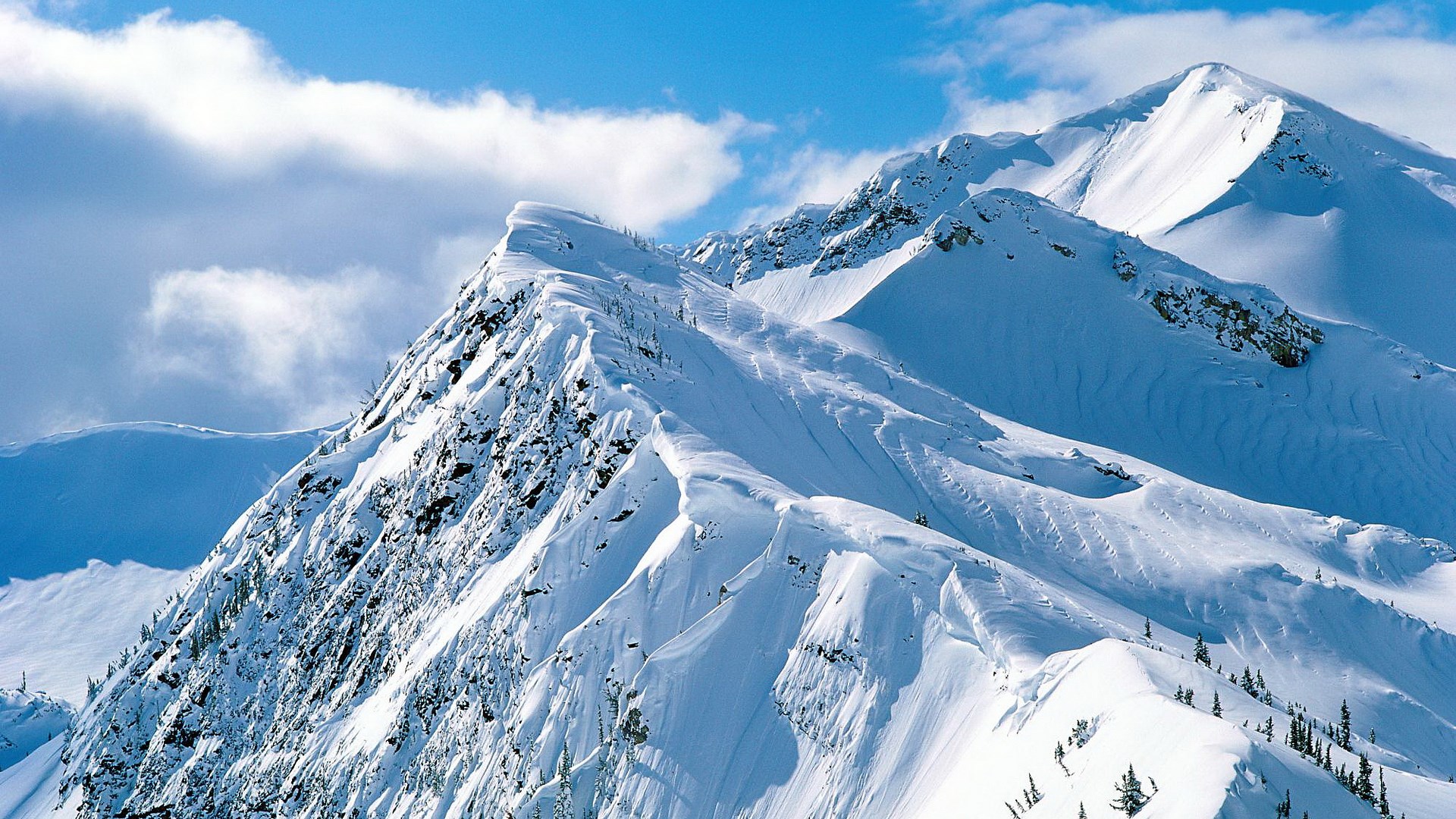 Snow-covered mountain range under a blue sky HD Wallpaper