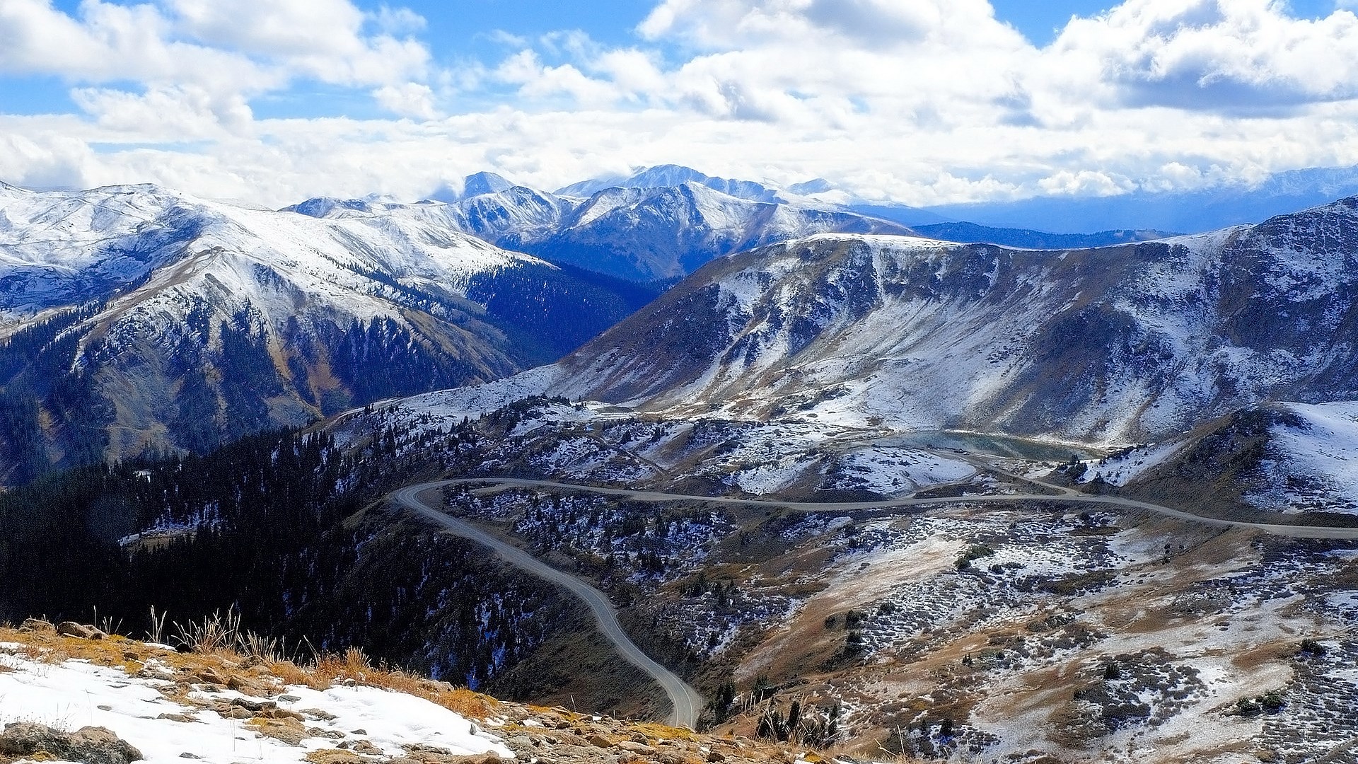 Snow-covered mountains with a winding road HD Wallpaper