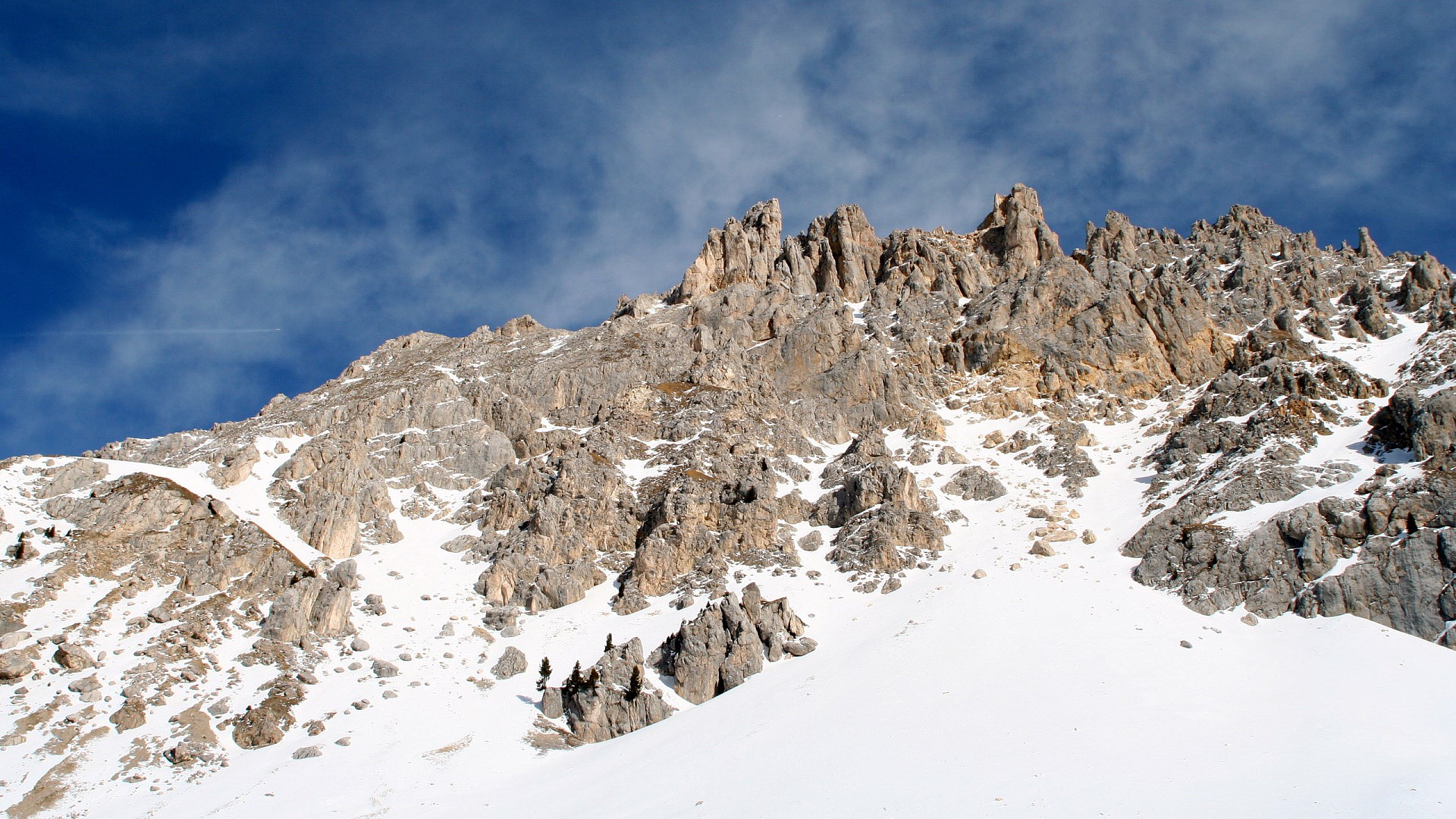 Snow-covered rocky mountain range under a blue sky HD Wallpaper