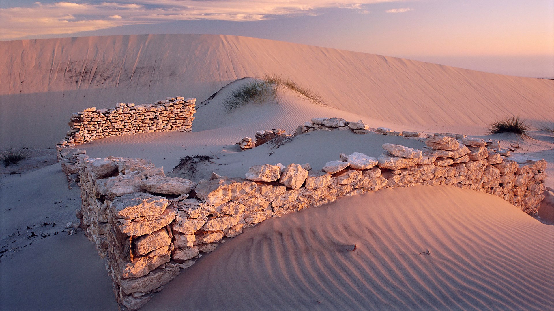 Ruins of a stone wall in a sand dune landscape at sunset HD Wallpaper