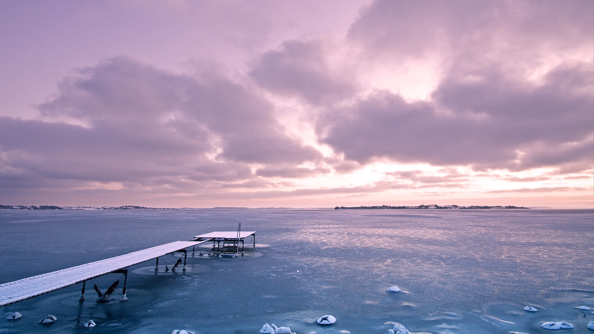 Frozen lake with a snow-covered pier at sunset HD Wallpaper