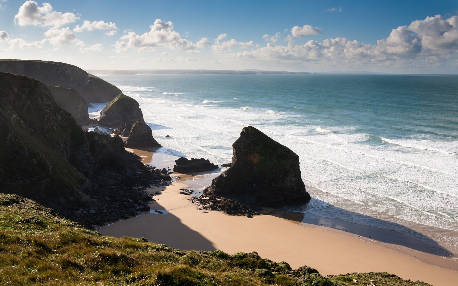 Rocky coastline with sandy beach and ocean waves HD Wallpaper