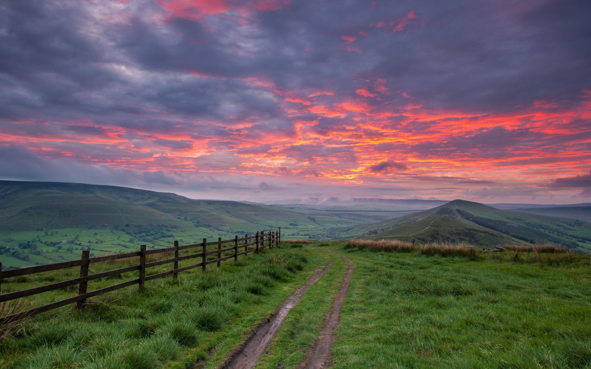Dramatic sunset over rolling hills with a wooden fence HD Wallpaper