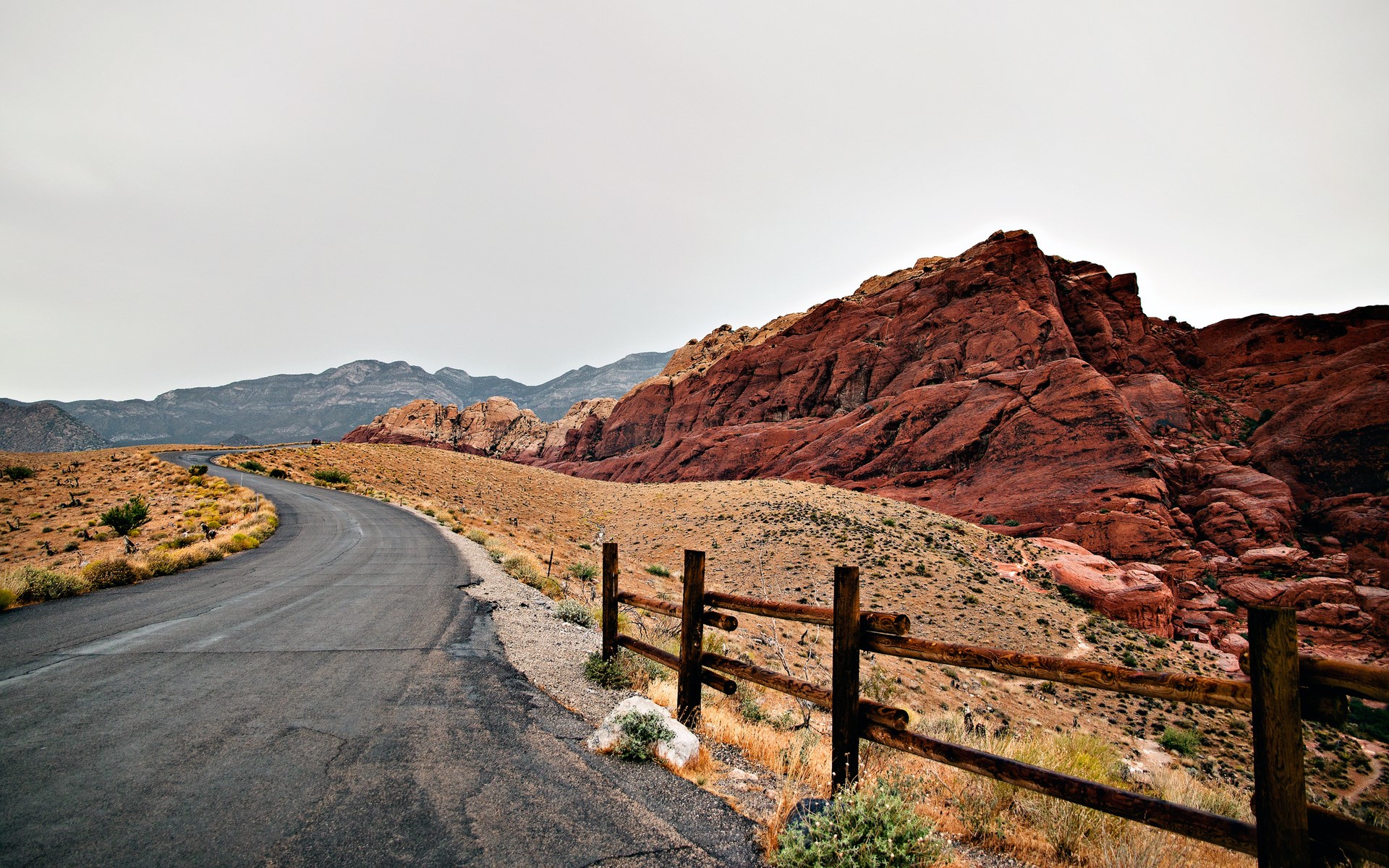 Desert road with red rock mountains and wooden fence HD Wallpaper