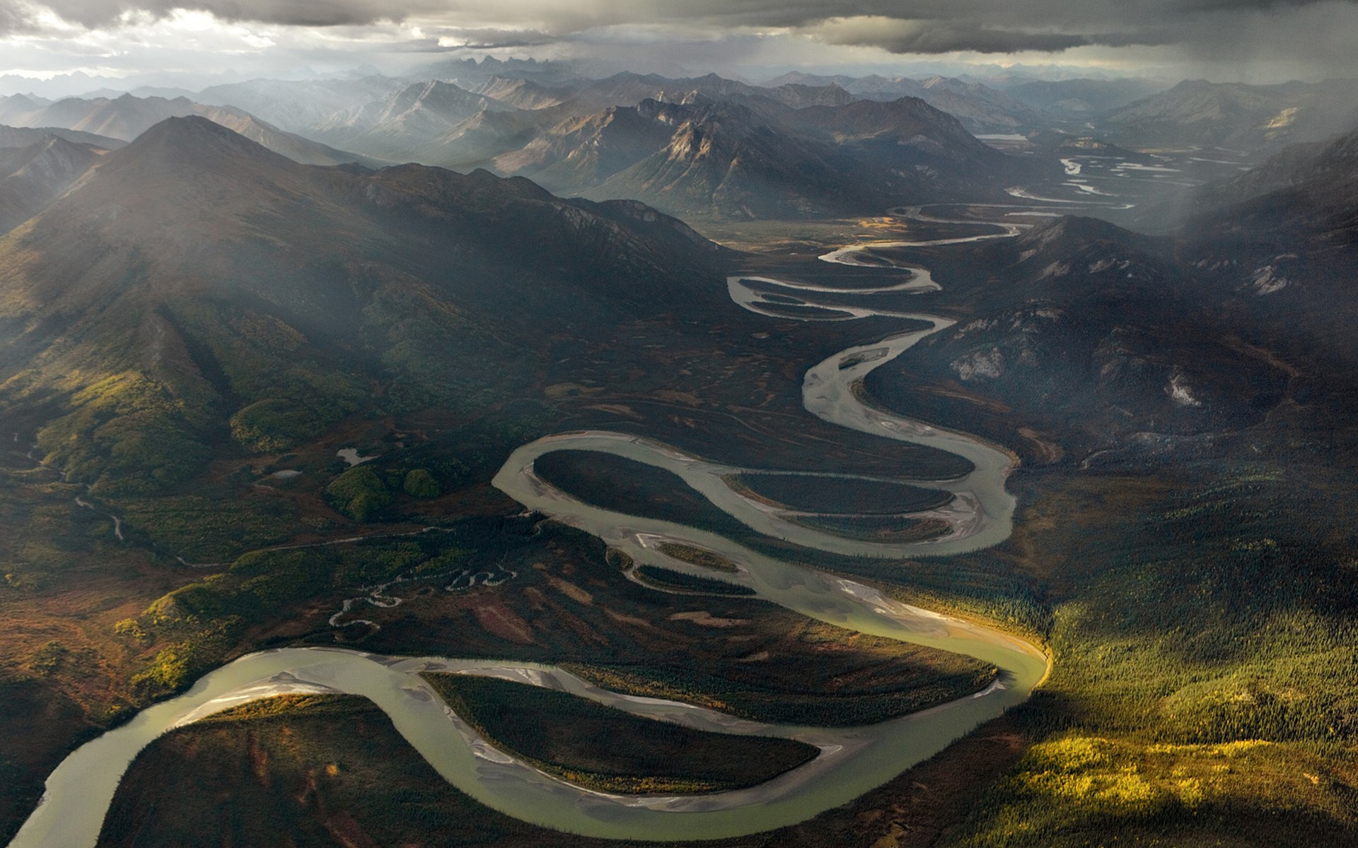 Aerial view of a winding river through mountains HD Wallpaper