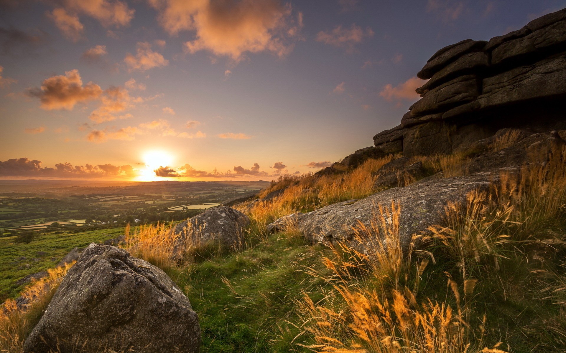 Sunset over a rocky, grassy hillside HD Wallpaper
