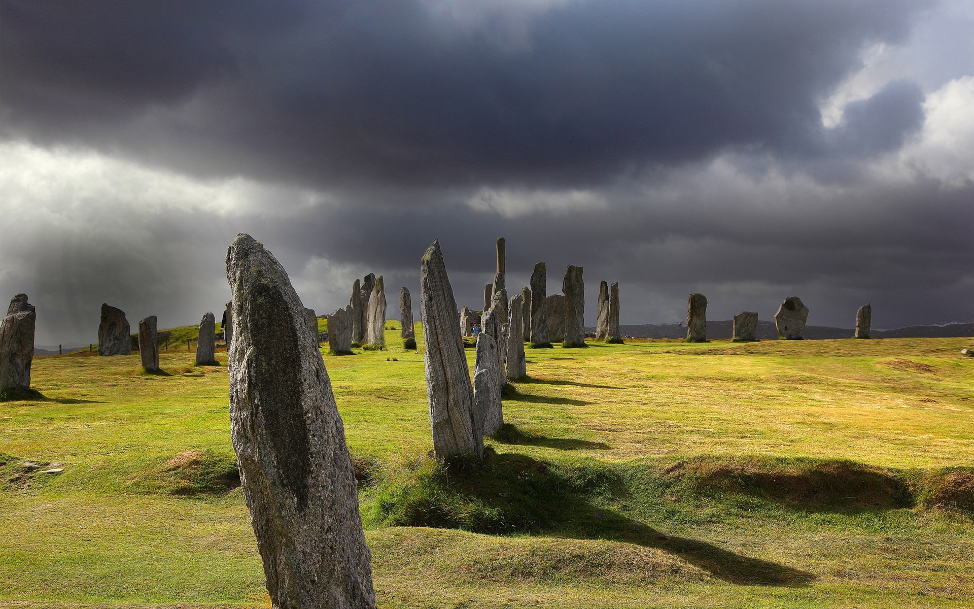 Standing stones on a grassy field under a stormy sky HD Wallpaper