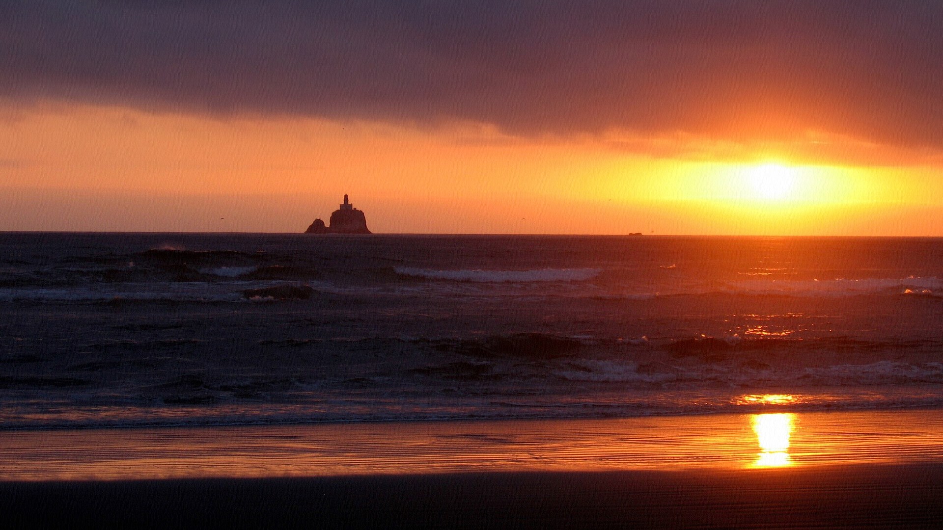 Sunset over the ocean with a lighthouse on a rock HD Wallpaper