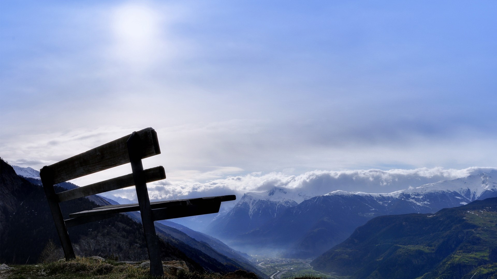 Wooden bench overlooking a misty mountain valley HD Wallpaper