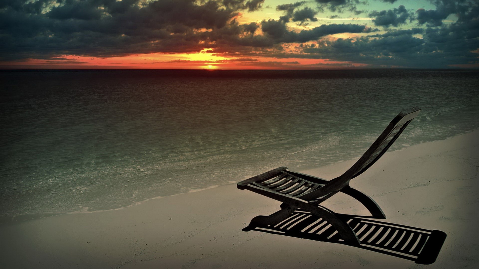 Empty lounge chair on a beach at sunset HD Wallpaper
