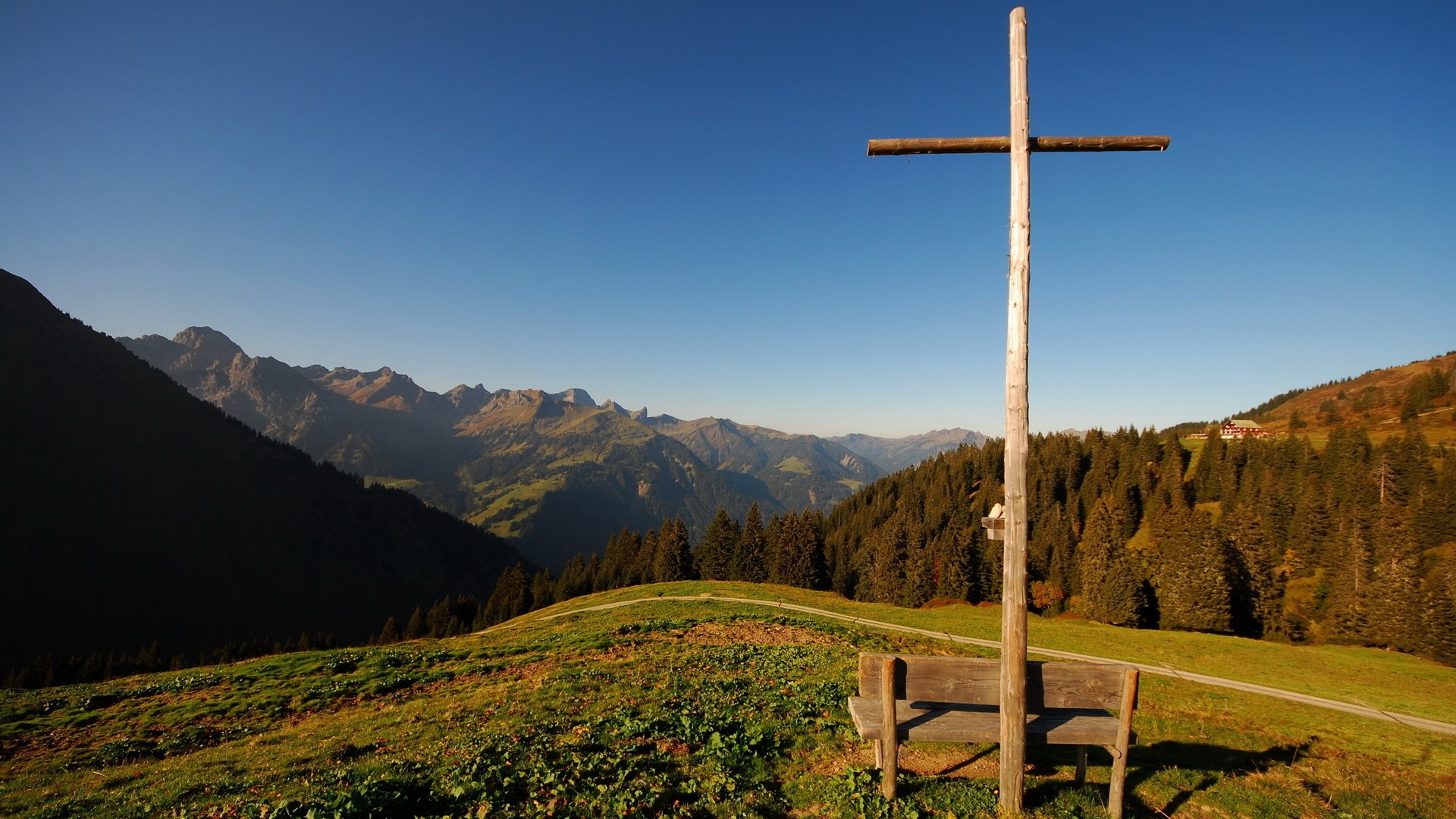 Wooden cross and bench on a mountain ridge HD Wallpaper