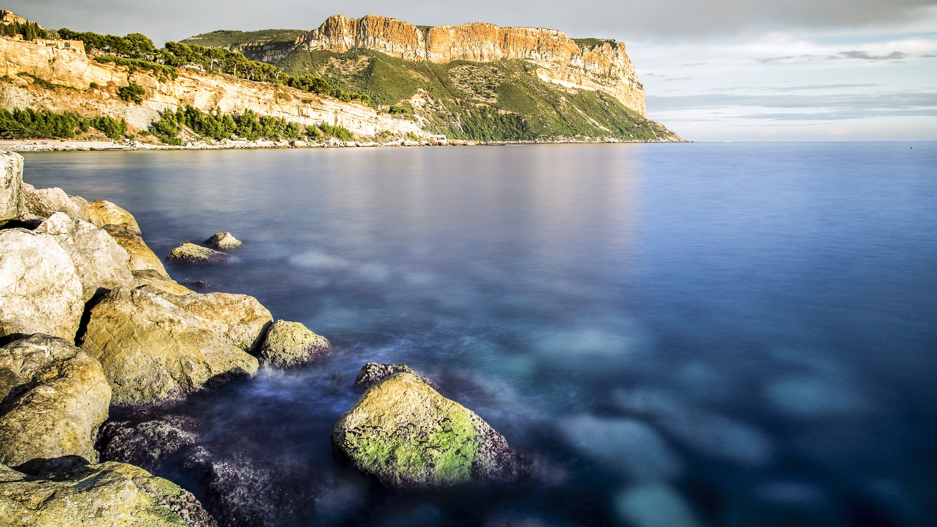 Rocky coastline with cliffs and blue sea HD Wallpaper
