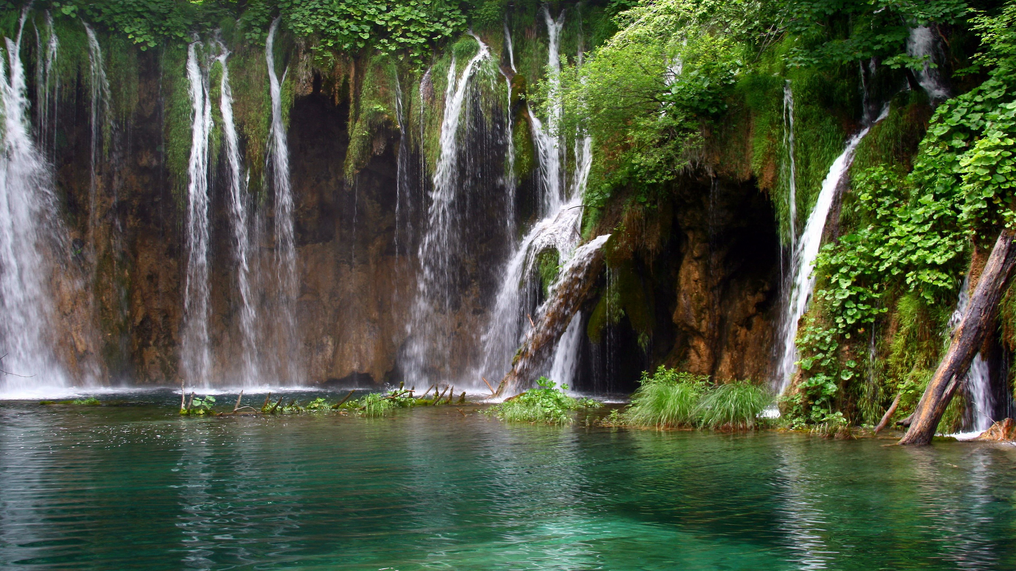 Waterfalls cascading into a clear turquoise lake HD Wallpaper
