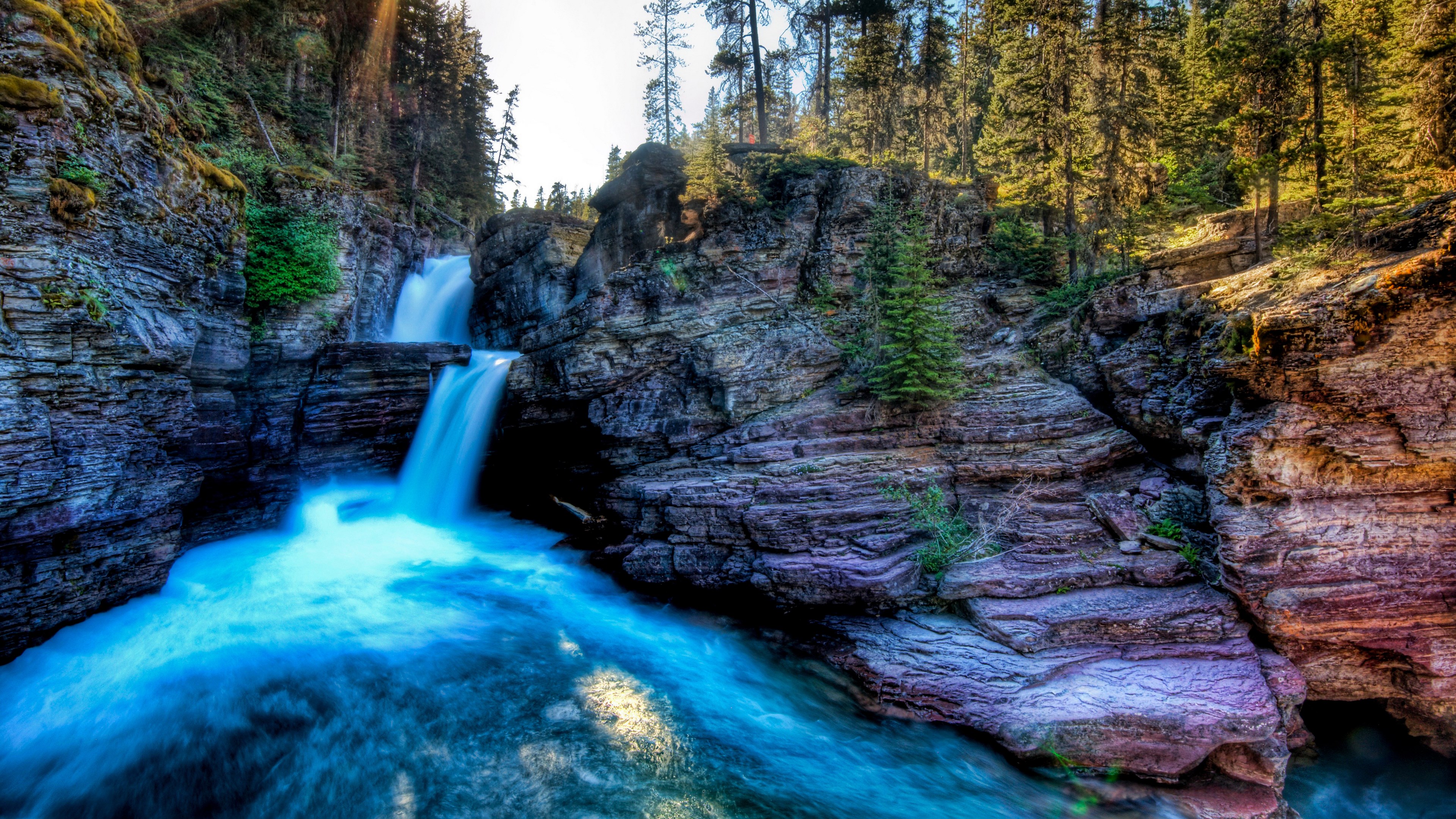 Waterfall cascading into a turquoise river in a rocky gorge HD Wallpaper