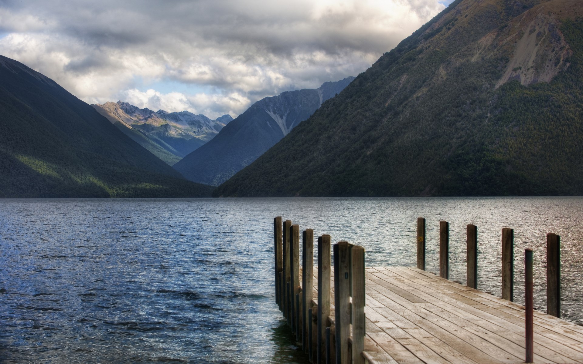 Wooden dock on a lake with mountains and clouds HD Wallpaper