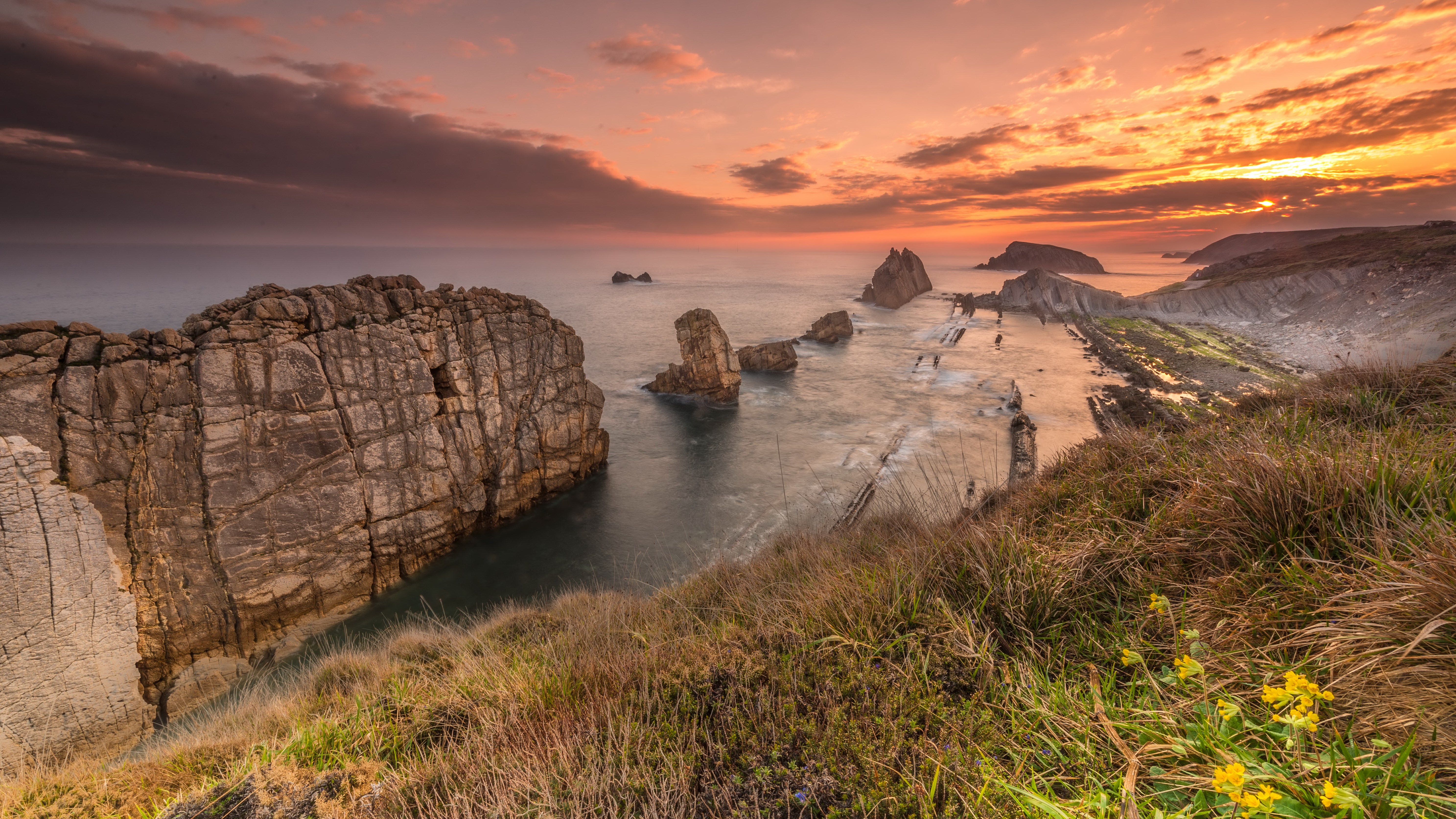 Rocky coastline at sunset with dramatic clouds HD Wallpaper