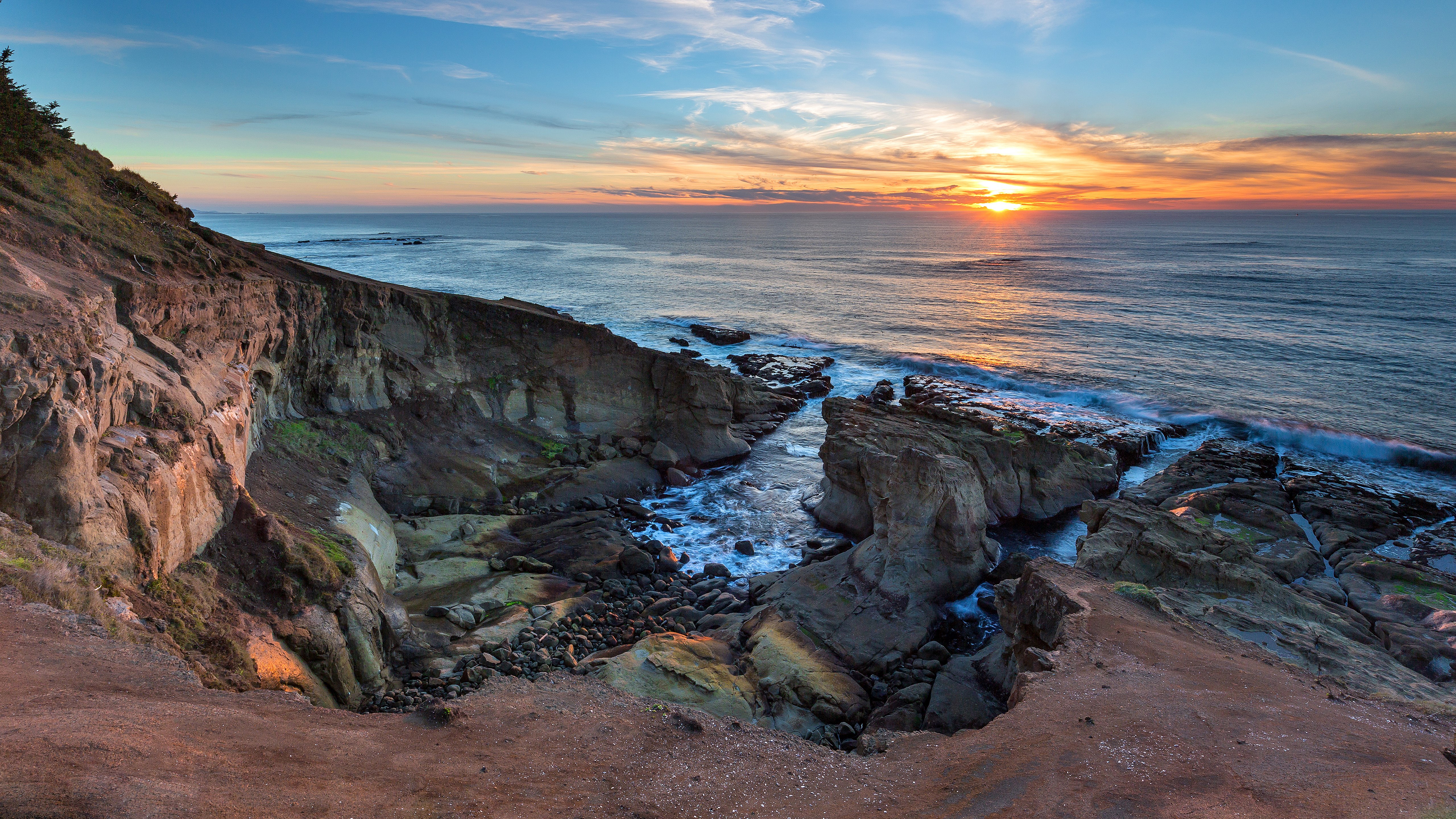 Sunset over rocky coastline with ocean waves HD Wallpaper