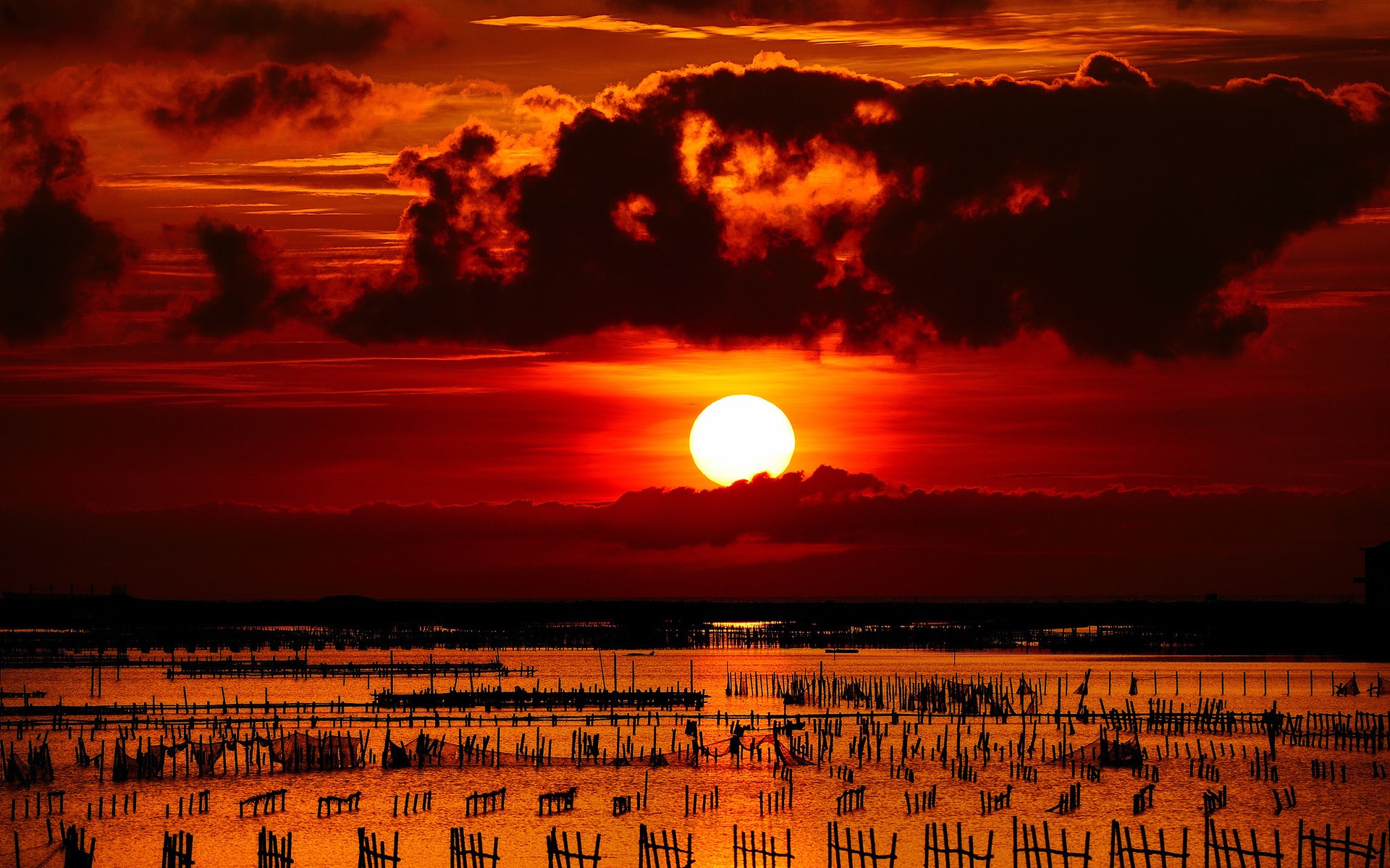 Sunset over a body of water with wooden structures HD Wallpaper