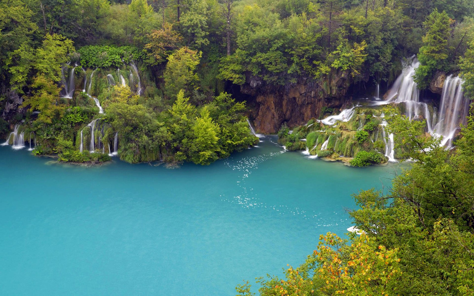 Turquoise lake with waterfalls and lush green forest HD Wallpaper