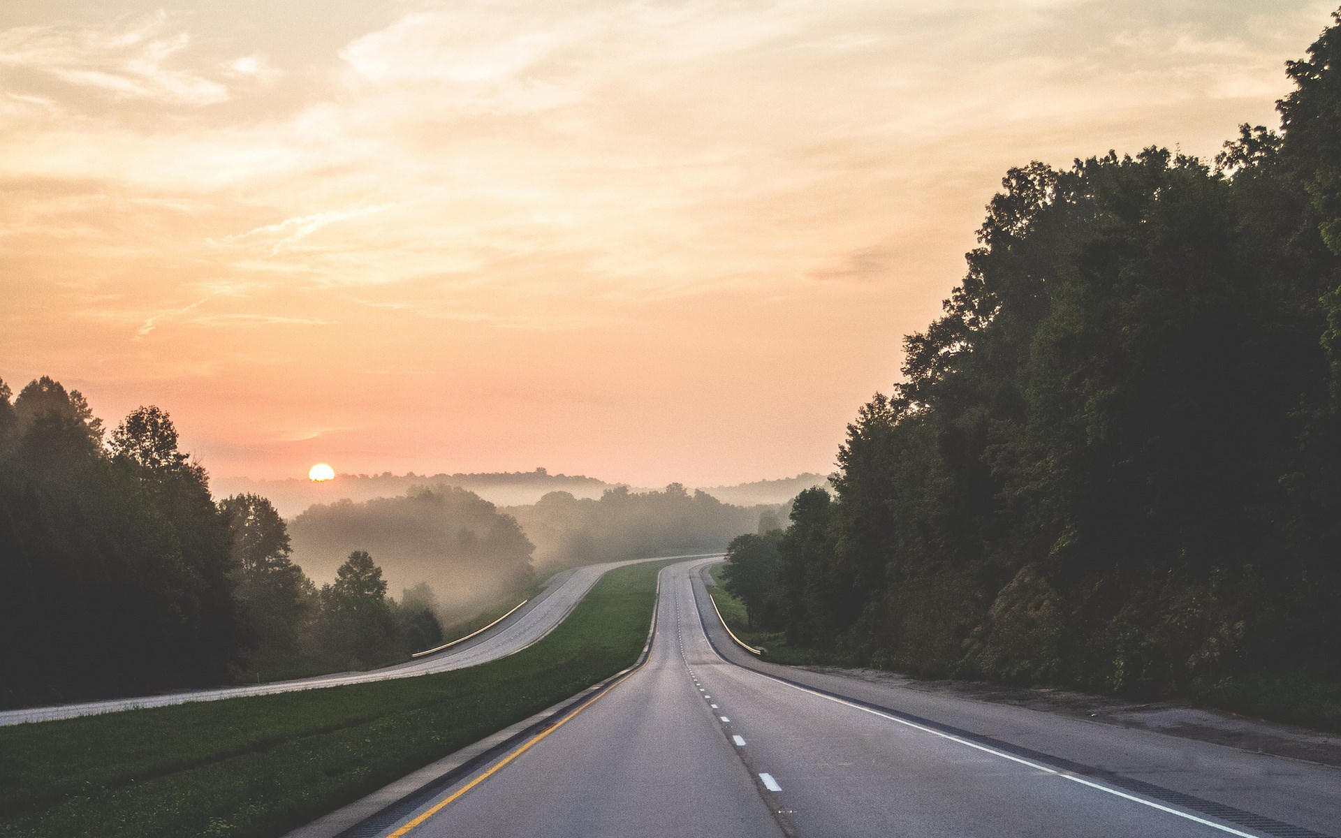 Winding road at sunrise with misty hills and trees HD Wallpaper