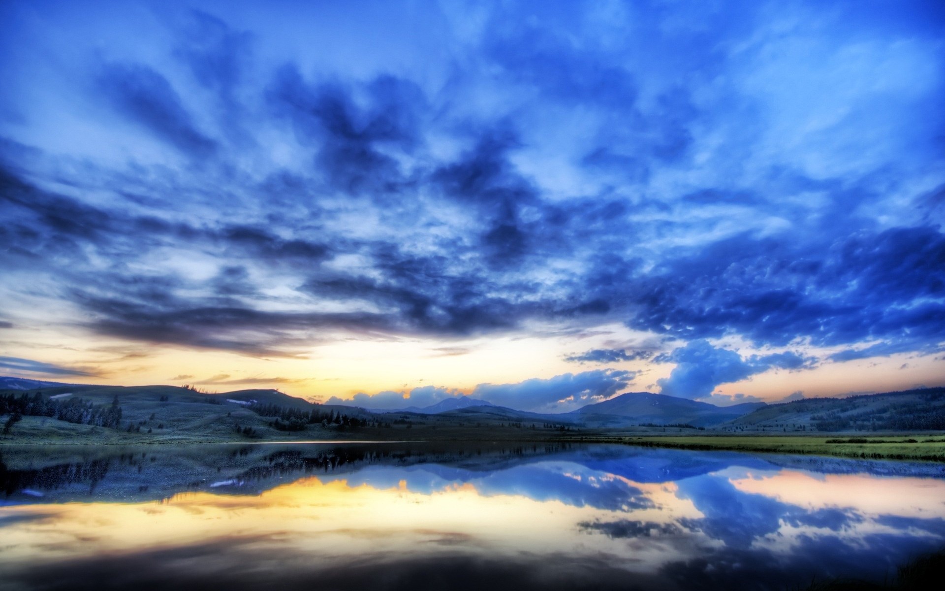 Sunset over a calm lake with mountains and clouds HD Wallpaper
