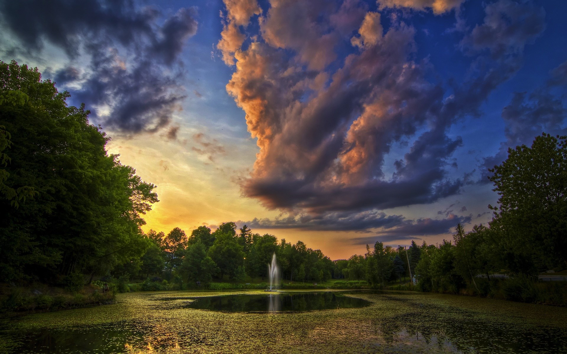 Pond with fountain and dramatic sunset clouds HD Wallpaper