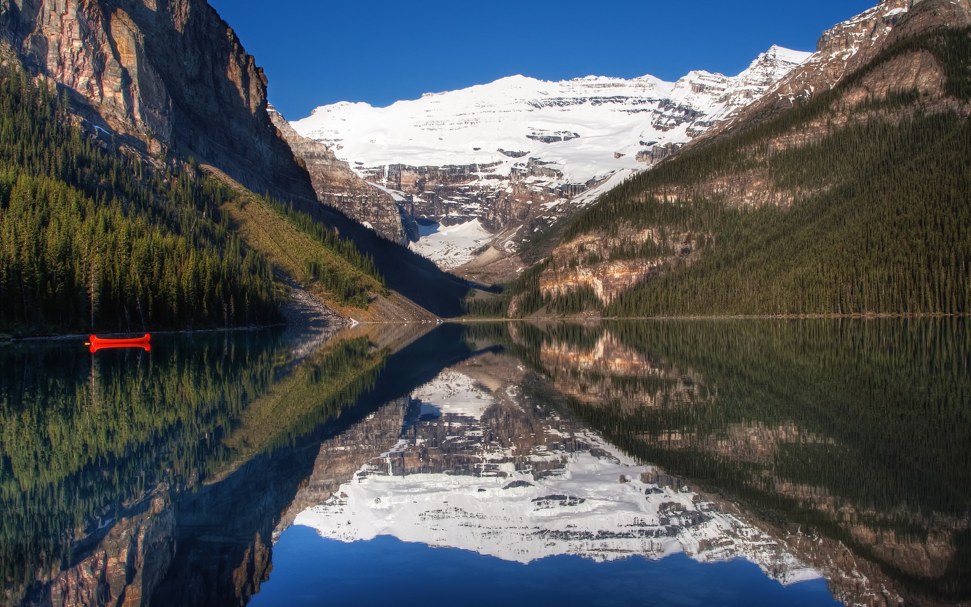 Red canoe on a calm lake with snow-capped mountains HD Wallpaper
