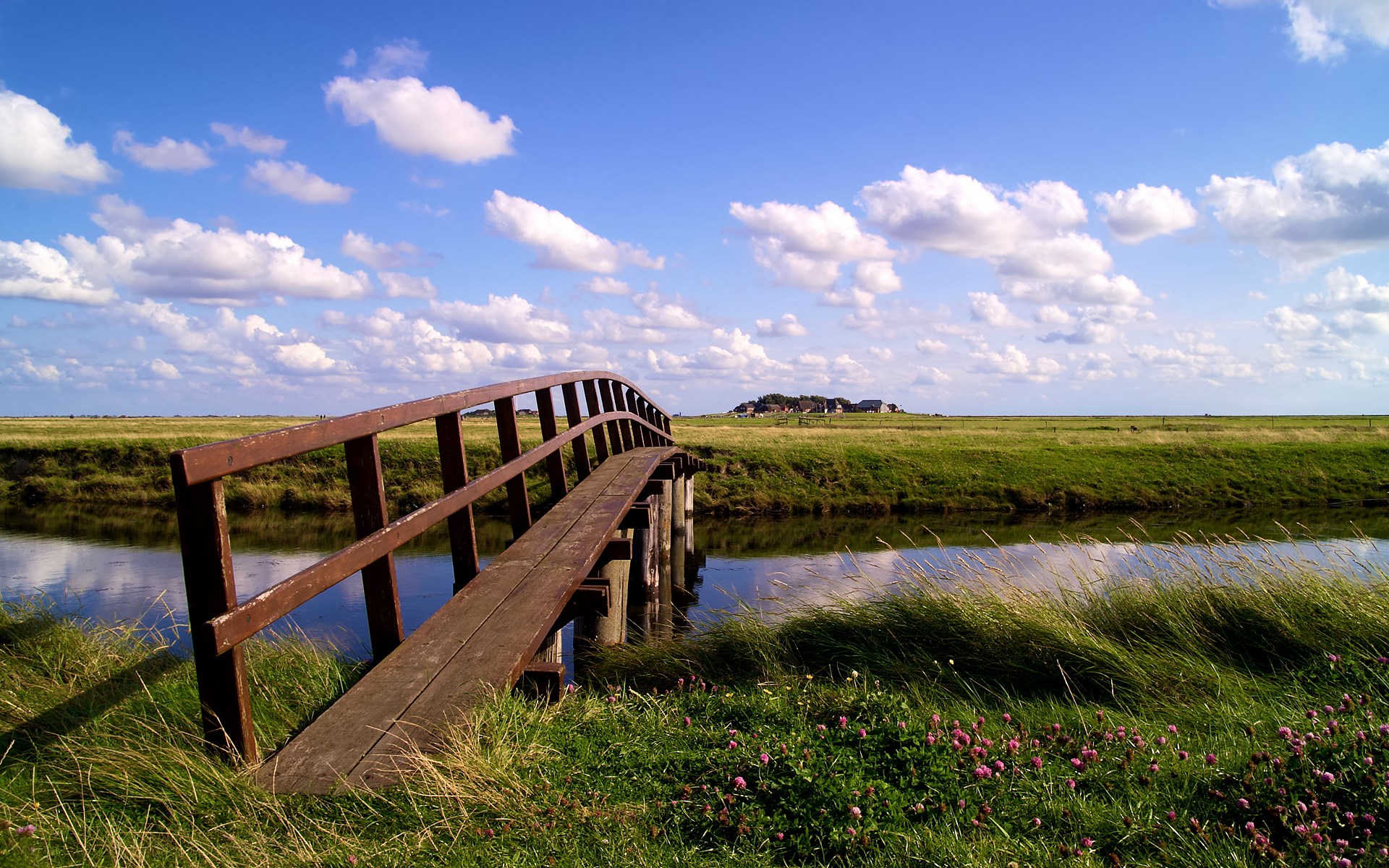Wooden bridge over a canal with green fields and clouds HD Wallpaper
