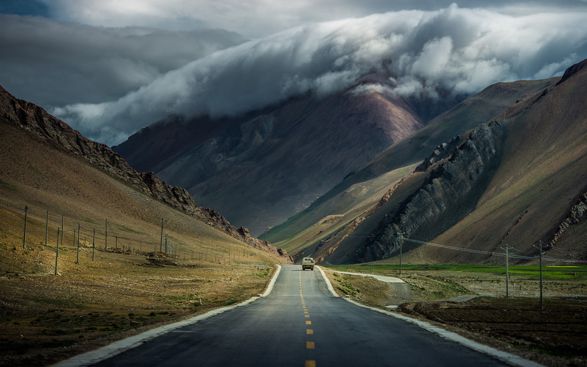 A car drives on a road through a mountain valley HD Wallpaper
